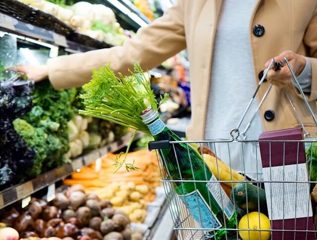 Woman shopping for groceries holding wire basket of produce