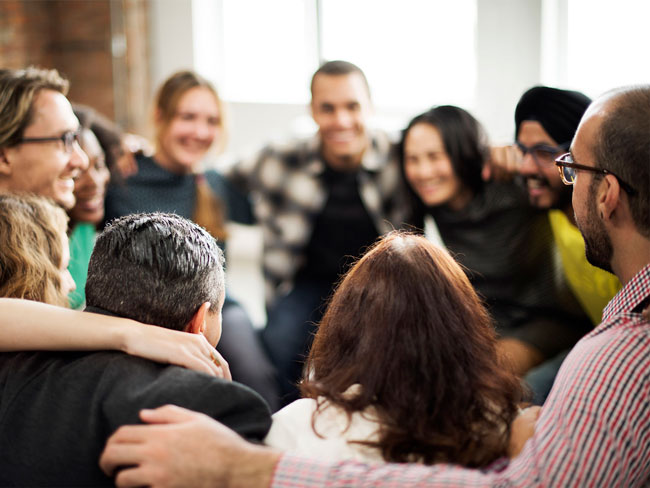 Team hugging at a retreat to build trust for remote teams and hybrid workplaces