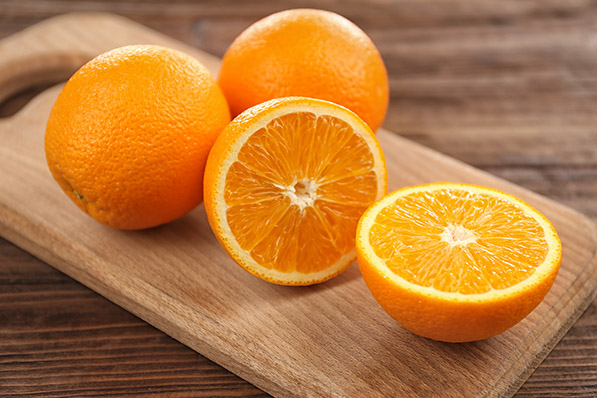 Oranges whole and sliced on cutting board