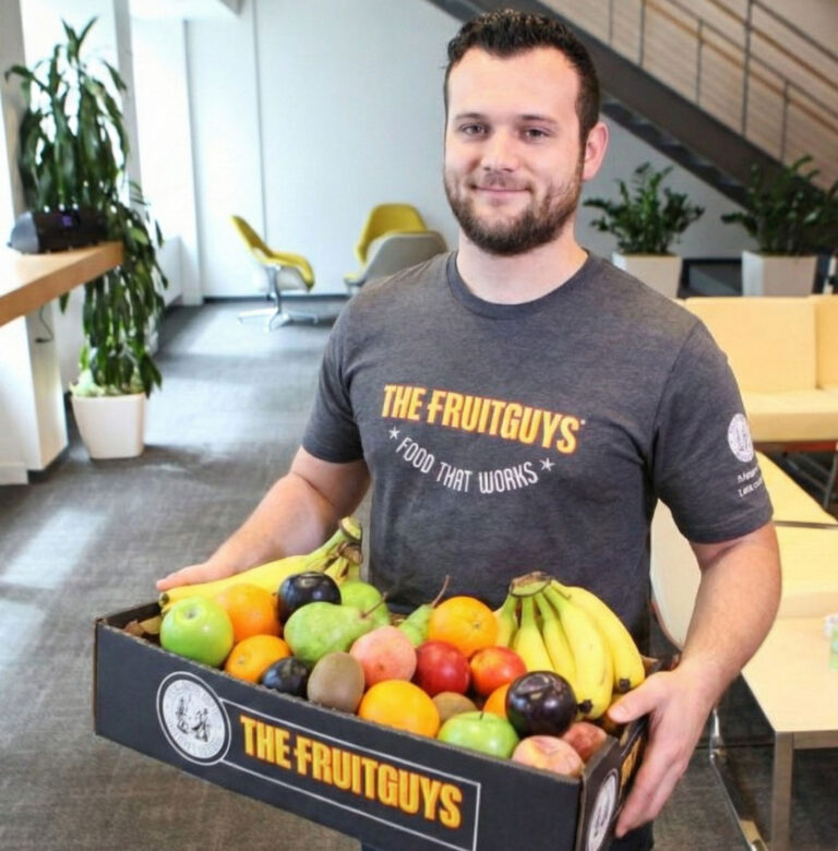 Man holding box of fresh fruit in an office