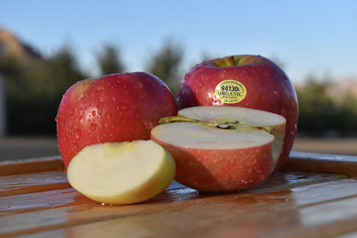 Whole and cut apples on a wooden table outdoors