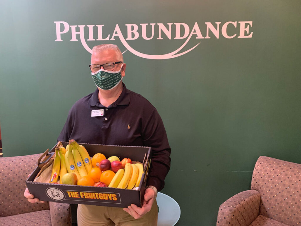 Staff at Philabundance Food Bank holding donated fruit box.