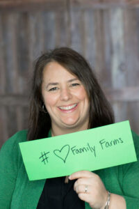 FruitGuys CEO Erin Mittelstaedt holding a "# heart Family Farms" sign