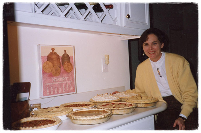 Woman smiling with counter full of pies