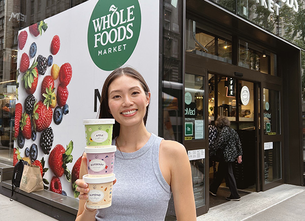 Smiling woman holding oatmeal cups outside of Whole Foods