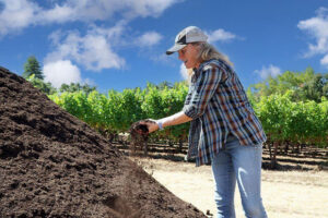 Woman holding a handful of compost beside a compost pile
