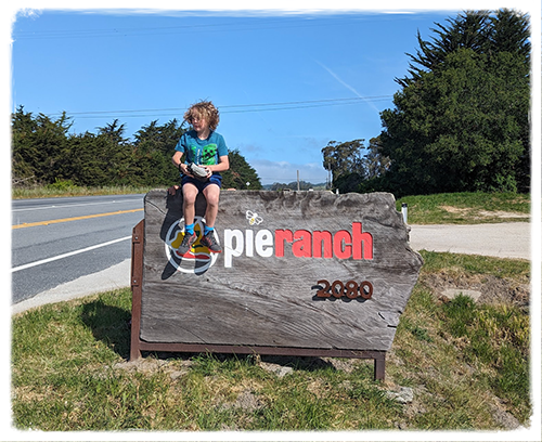 Kid sitting on the Pie Ranch sign