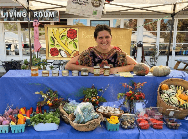 Smiling farmer standing at farmers market display