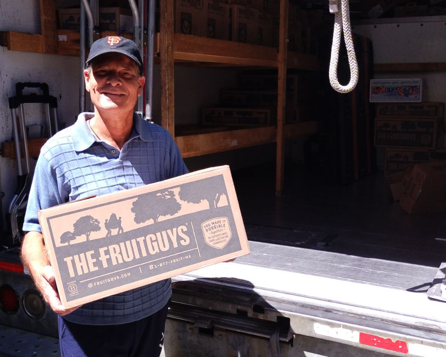 Fresh fruit delivery driver holding The FruitGuys box