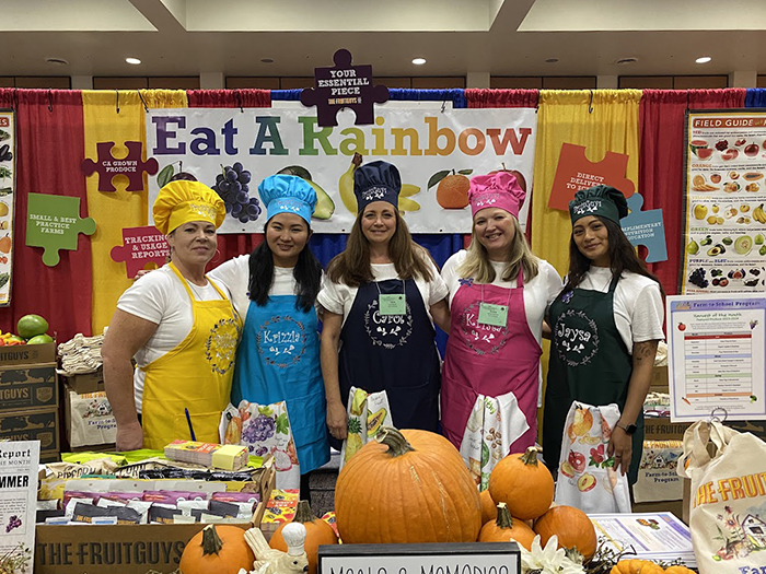 Five schools team members at the CSNA Booth; Eat a Rainbown sign in the background