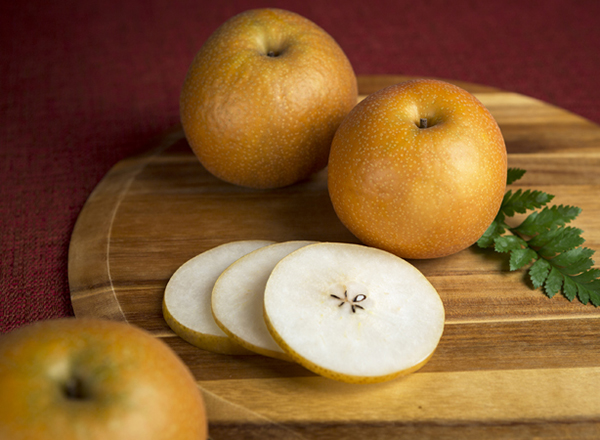 Whole and sliced Asian pears on a cutting board