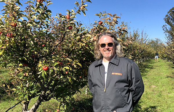 Man in The FruitGuys jacket standing in orchard