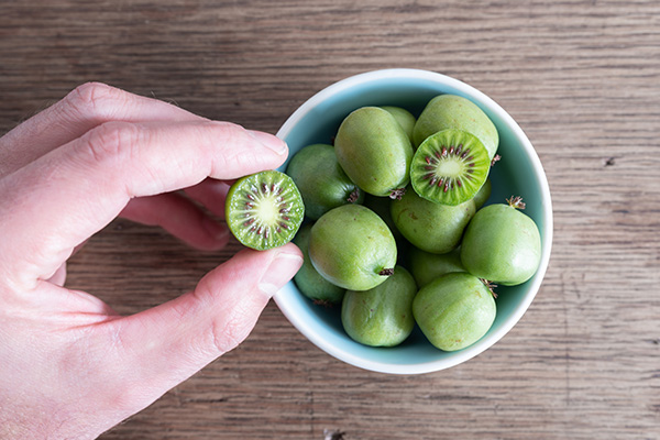 hand reaching into a bowl of kiwi berries
