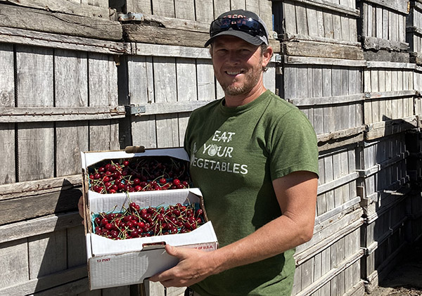 Man smiling holding box of cherries