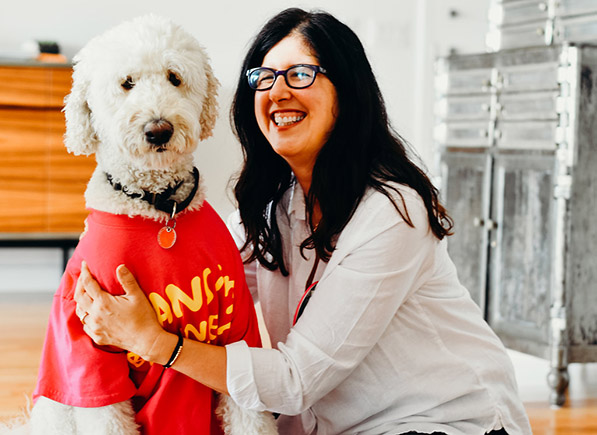 Woman smiles, hugging dog in a T-shirt