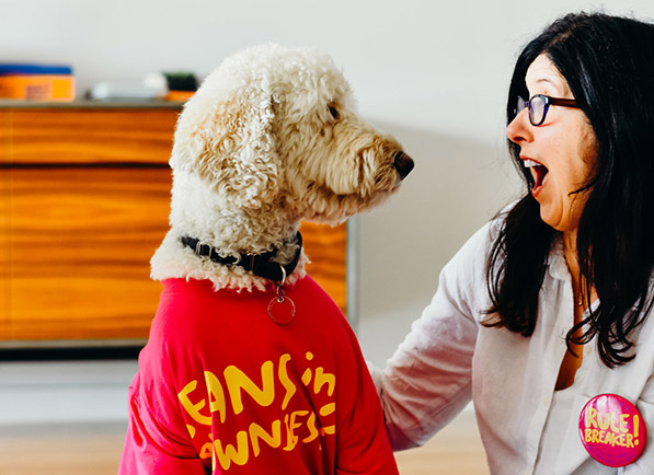 Woman gasps, looking at dog in a T-shirt