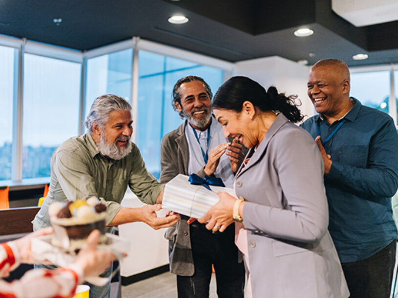 Woman receiving gift surrounded by coworkers