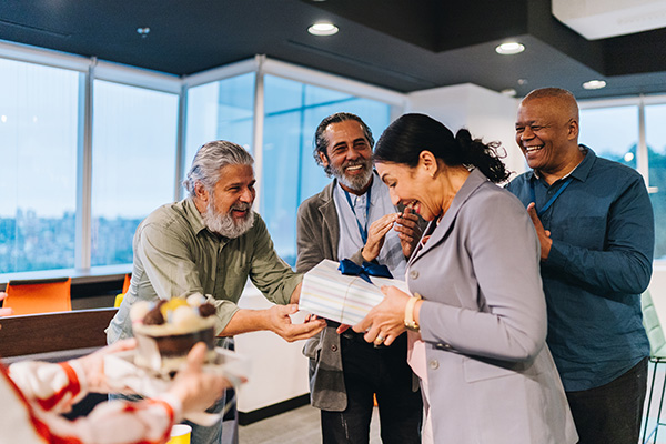 Happy employee receiving gift surrounded by coworkers