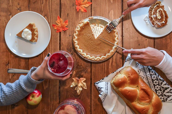 Hands serving food and holding drinks at Thanksgiving table