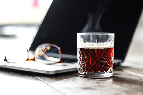 Steaming drink next to a laptop and glasses