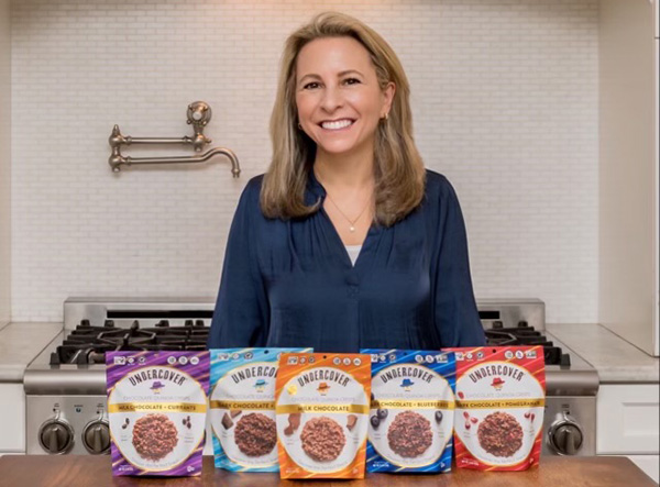 Woman smiling in front of bags of Undercover Snacks