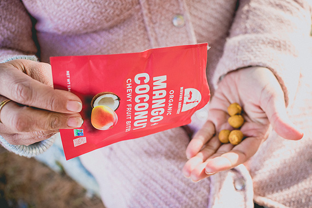 Person pouring Mavuno Harvest Mango + Coconut Chewy Fruit Bites into their hand