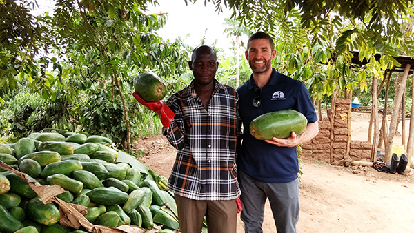 Two smiling men holding papayas