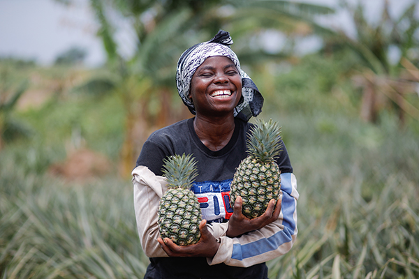 Smiling woman holding pineapples