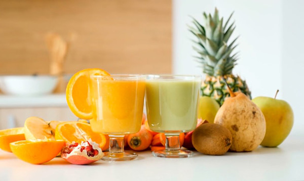 Fresh-squeezed fruit and vegetable juice on counter surrounded by produce