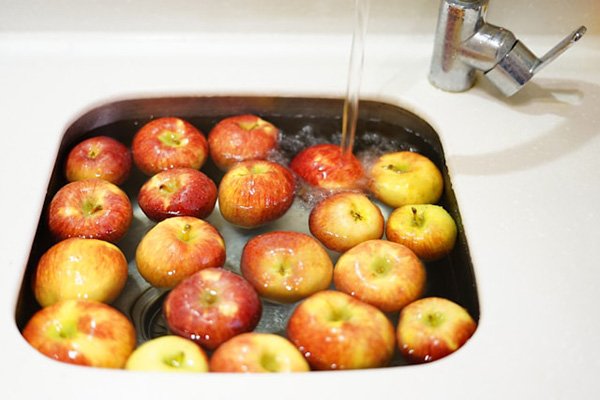 Washing apples incorrectly by filling a sink with water and soaking them