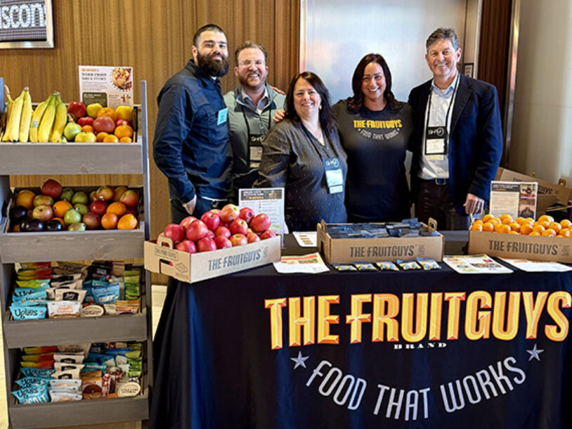 The FruitGuys team behind a booth of fresh fruit and snacks