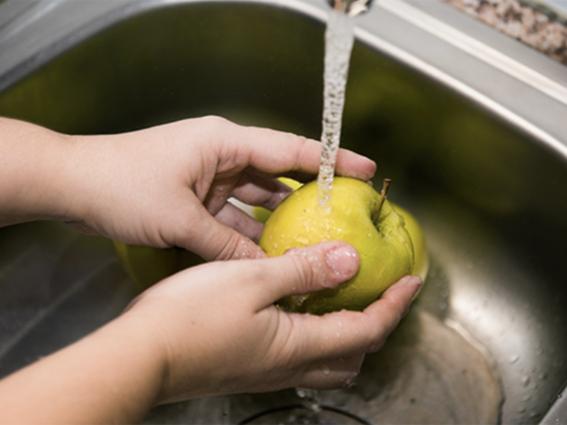 Person washing apple in sink