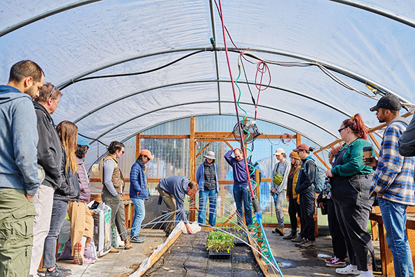 Farmers and learners standing in a hoop house