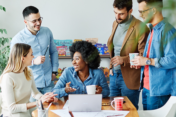 Smiling employees in the break room with office snacks in the background