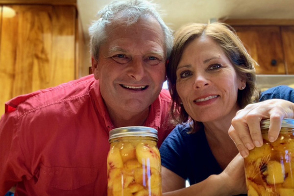 Smiling peach farmers with cans of peaches