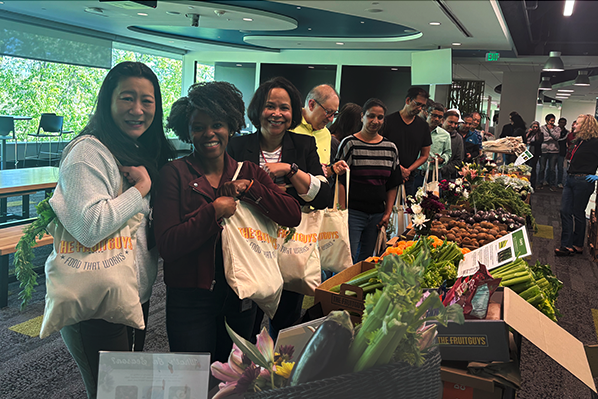 Smiling employees getting free produce at an office farmers market