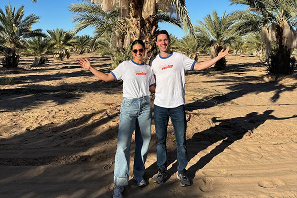 Smiling man and woman in front of a grove of trees