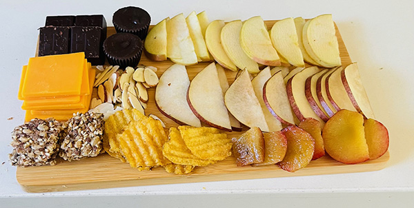Charcuterie board with fruit, chocolate, cheese, chips, and other snacks