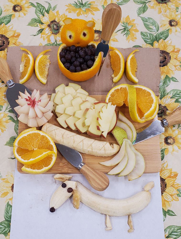 Charcuterie board with fruit cut and arranged in the shapes of flowers and animals