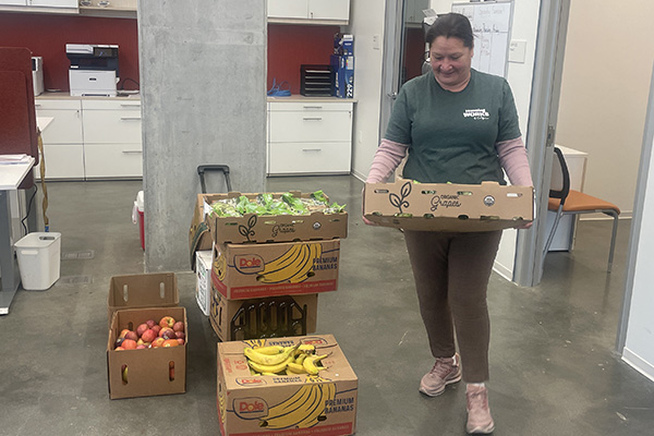 Woman carrying a tray of fresh fruit beside boxes of fruit