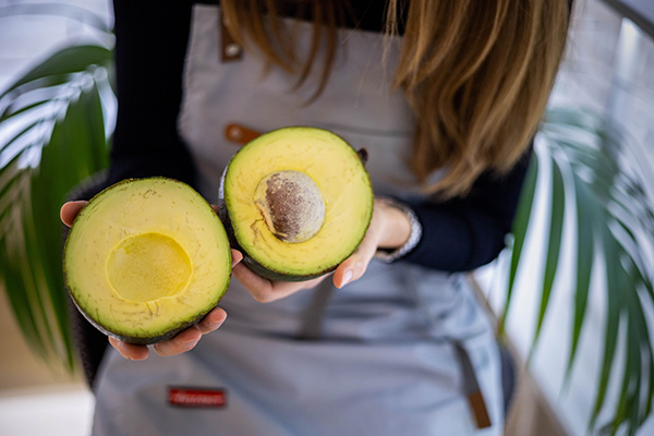 Woman holding big round avocado cut in half