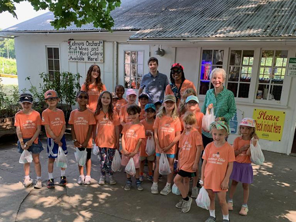 Smiling kids and teachers in front of a farm building