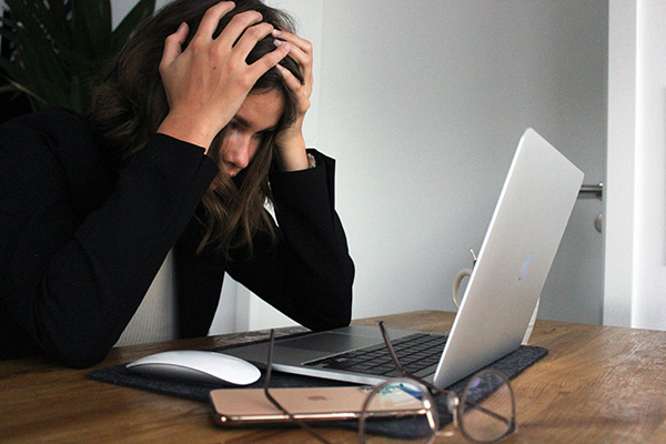 Stressed employee in front of a laptop, holding her head