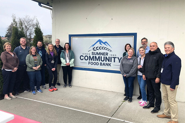 People standing in front of a Sumner Community Food Bank sign