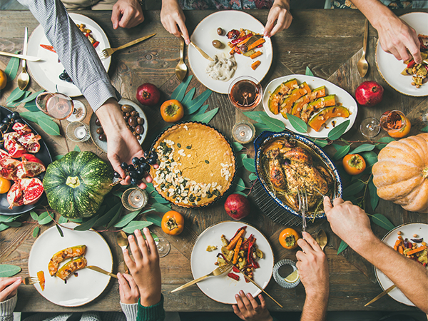 Thanksgiving table full of food, hands reaching in