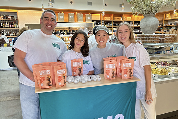 Smiling people behind a demonstration table for Whims chocolates