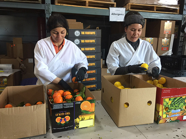 Smiling women sorting boxes of fresh fruit