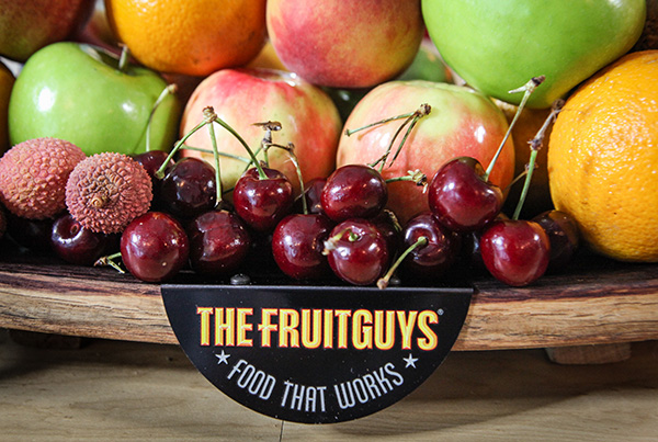 Fresh fruit in a The FruitGuys bowl, including cherries, nagosteens, oranges, apples