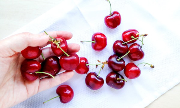 Cherries spilling out of hand onto white cloth
