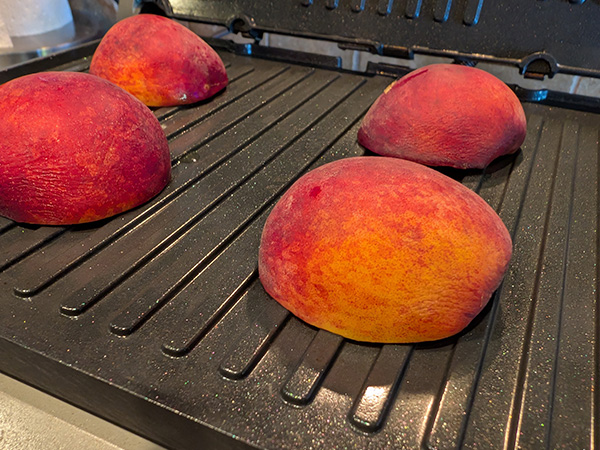 halved peaches on a grill